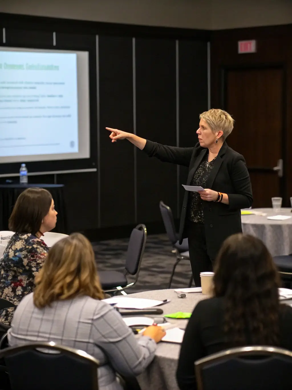A photograph of a business coach leading a workshop, with participants actively engaged in discussions and collaborative problem-solving, illustrating the collaborative nature of the Premium Package.